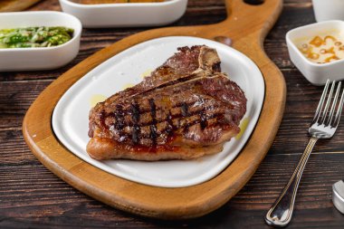 Tahta masada çeşitli aperatiflerle T-Bone bifteği