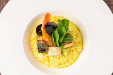 Deniz mahsullü risotto, risotto alla pescatora, beyaz bir porselen tabakta servis edilir.