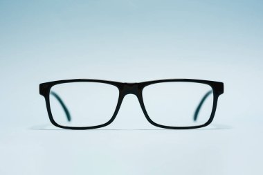 Mavi arkaplanda plastik siyah çerçeveli reçeteli gözlüklerin ön görünümü