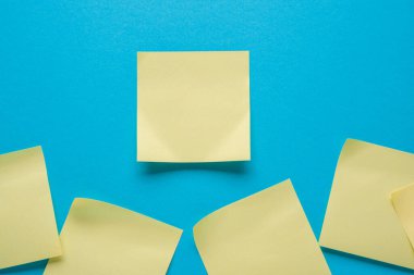 Mavi arkaplanda boş sarı yapışkan bir not