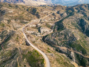 Sonbaharda çok az ağacın olduğu bölgelerden geçen dolambaçlı bir asfalt yol. S-kıvrımlı bir otoyol