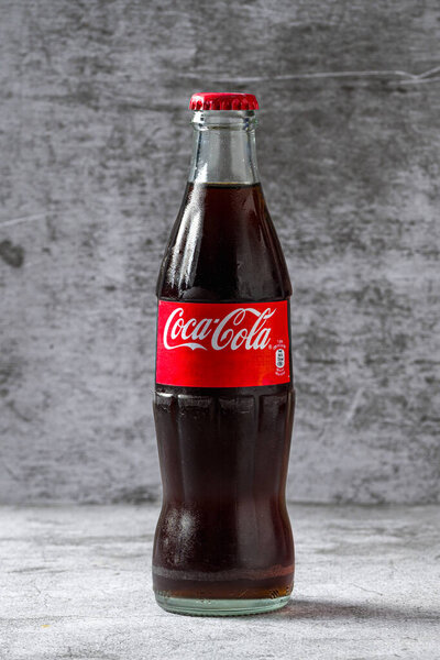 Antalya, Turkey - November 7, 2023: Classic glass Coca-Cola bottle on stone table
