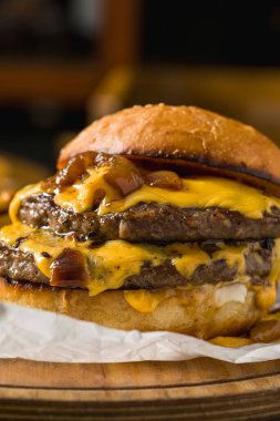 Çedar peynirli ve karamelli soğanlı ezme burger, patates kızartmasıyla servis edilir.