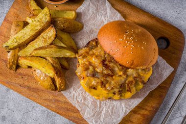 Smash burger with cheddar cheese and caramelized onions, served with fries clipart