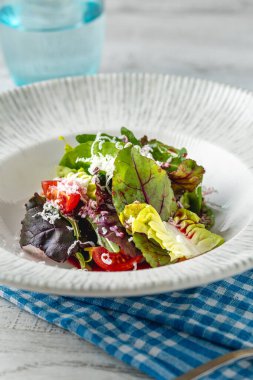 Beyaz porselen tabakta karışık mevsimlik yeşil salata.