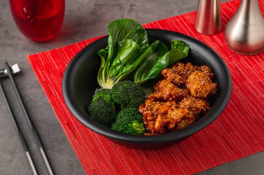 Brokolili Teriyaki tavuk kasesi ve gri taştan masada bok çuvalı.