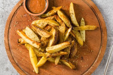 Spicy French fries with hot sauce on a cutting board clipart