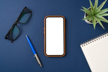 Mavi masadaki boş ekran akıllı telefon. Not defteri, kalem ve bardaklar.