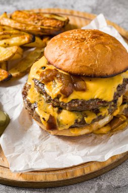 Çedar peynirli ve karamelli soğanlı ezme burger, patates kızartmasıyla servis edilir.