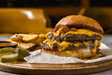Çedar peynirli ve karamelli soğanlı ezme burger, patates kızartmasıyla servis edilir.