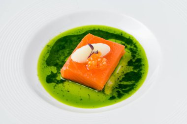 Sous-vide somon fileto ile balık yumurtası, şerbet ve mikro yeşilliklerle süslenmiş, canlı yeşil bitki sosu ile servis edilir.