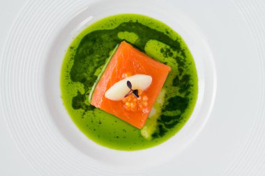 Sous-vide somon fileto ile balık yumurtası, şerbet ve mikro yeşilliklerle süslenmiş, canlı yeşil bitki sosu ile servis edilir.