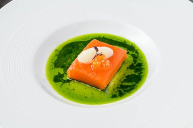 Sous-vide somon fileto ile balık yumurtası, şerbet ve mikro yeşilliklerle süslenmiş, canlı yeşil bitki sosu ile servis edilir.