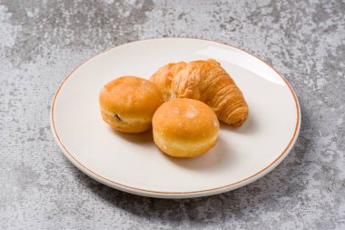 Mini berliner veya Alman çörekleri ve kruvasan beyaz tabakta taş masada.