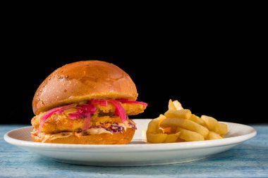 Beyaz porselen tabakta patates kızartmalı leziz tavuk burger.