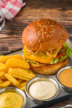 Patates kızartması ve sosla servis edilen kızarmış soğanlı ezme burger.