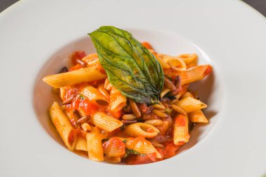 Klasik İtalyan makarna penne alla arrabiata ile fesleğen ve sos koyu gri masada. Baharatlı arrabbiata soslu makarna.