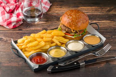 Patates kızartması ve sosla servis edilen kızarmış soğanlı ezme burger.