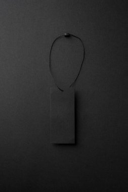 Siyah arkaplanda sicim olan boş siyah karton elbise etiketi