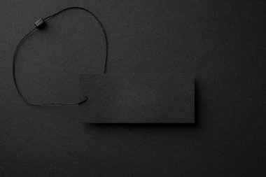 Siyah arkaplanda sicim olan boş siyah karton elbise etiketi