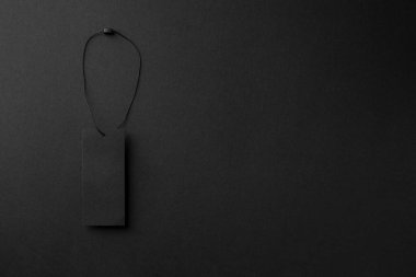 Siyah arkaplanda sicim olan boş siyah karton elbise etiketi