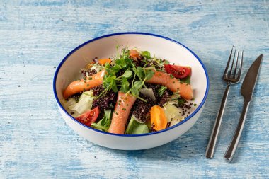 Sağlıklı kinoa salatası, füme somon, kiraz domatesleri ve taze yeşillikler.