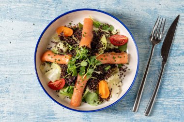 Sağlıklı kinoa salatası, füme somon, kiraz domatesleri ve taze yeşillikler.