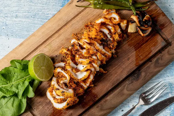 Izgara kalamar ahşap kesme tahtasındaki süslerle halka şeklinde kesilmiş.