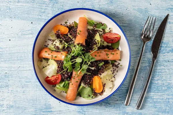 Sağlıklı kinoa salatası, füme somon, kiraz domatesleri ve taze yeşillikler.