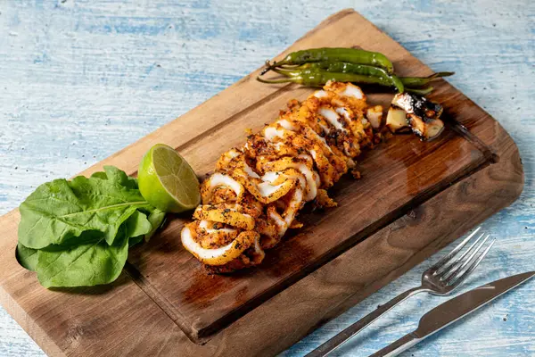 Izgara kalamar ahşap kesme tahtasındaki süslerle halka şeklinde kesilmiş.