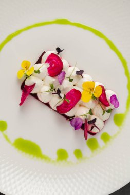 Keçi peyniri ve yenilebilir çiçeklerle süslenmiş renkli pancar dilimleri.