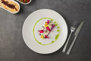 Keçi peyniri ve yenilebilir çiçeklerle süslenmiş renkli pancar dilimleri.