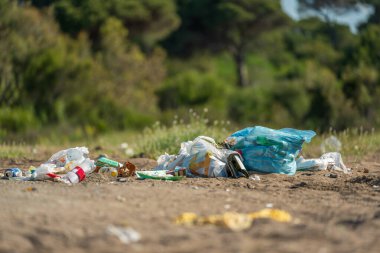Plastik torbalar ve şişeler deniz kenarındaki kumlu bir plaja atıldı.