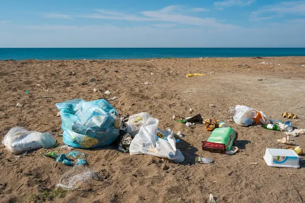 Plastik torbalar ve şişeler deniz kenarındaki kumlu bir plaja atıldı.