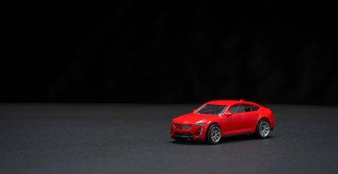 Kırmızı minyatür oyuncak araba, karanlık bir yüzeye yakın plan çekilmiş.