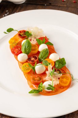 Fesleğen ve otlarla süslenmiş domates ve mozzarella düzenleme.