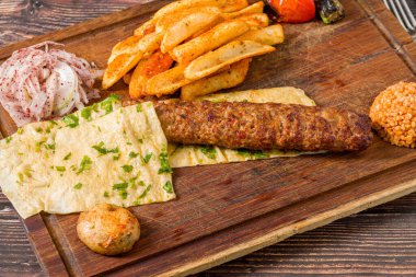 Geleneksel Adana kebabı patates, lavaş, bulguru ve soğan salatası.