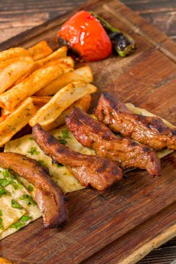 Izgara kuzu fileto ya da kızarmış patates, lavaş ekmeği ve bulgur pilavı ile servis edilen Lamb Kusleme.