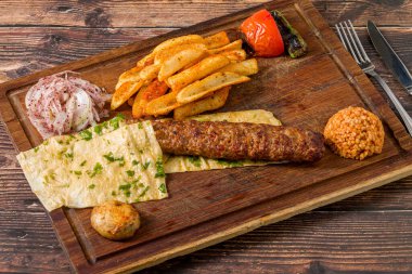 Geleneksel Adana kebabı patates, lavaş, bulguru ve soğan salatası.