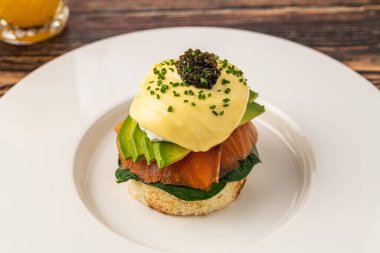 Beyaz tabakta füme somon ve havyarlı gurme yumurtalı Benedict.
