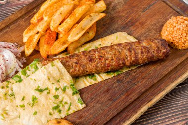 Geleneksel Adana kebabı patates, lavaş, bulguru ve soğan salatası.