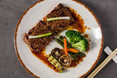 Izgara sebze ve baharatlı sosla servis edilen baharatlı biftek.