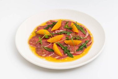 İnce dilimlenmiş et carpaccio portakal dilimleri ve roka yapraklarıyla.