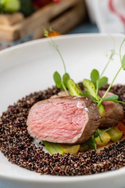 Medium rare beef steak with asparagus and vegetables on quinoa
