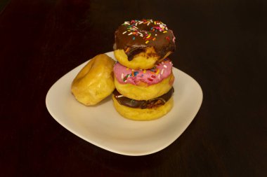 Çilekli, çikolatalı ve kremalı çeşitli tatlardaki çörekler renkli şekerlemelerle. Şekerleme grubuna yaslanmış donutlu gurme fotoğrafçılığı..