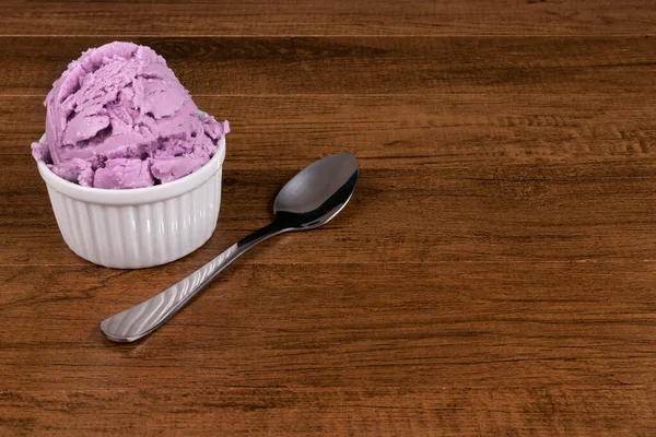木のテーブルの上にスプーンが付いているグレープ風味の紫色のアイスクリーム テキスト用のフリースペース付きグルメ写真 — ストック写真