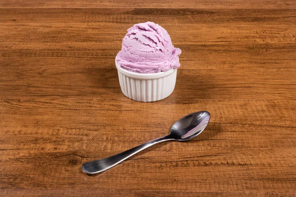 Grape-flavored purple ice cream served in the pot. A ball of ice cream accompanied by a spoon. Center-aligned elements with free side spaces for text.