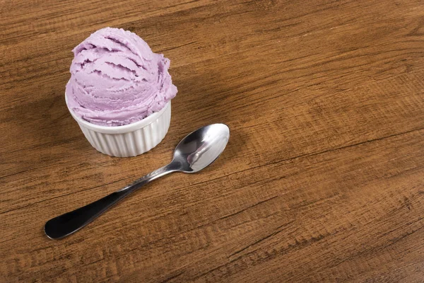 Grape-flavored purple ice cream served in the pot. A ball of ice cream accompanied by a spoon. Left-aligned elements.