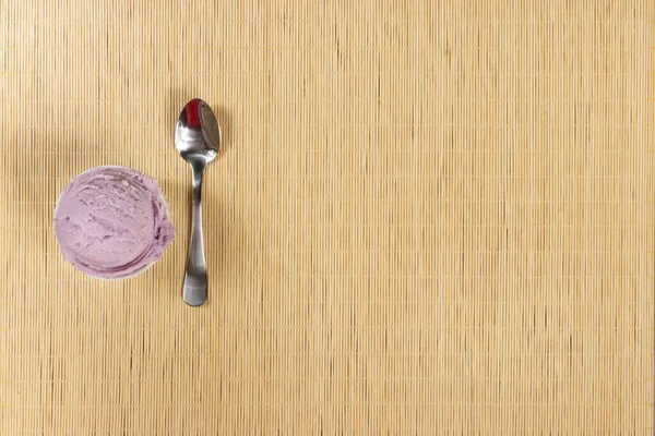 Grape-flavored purple ice cream served in white pot with spoon on the side. Top gastronomic photography with empty text space for text on the right.