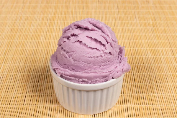 A scoop of grape-flavored purple ice cream served in a white bowl. Close-up of gastronomic photography.
